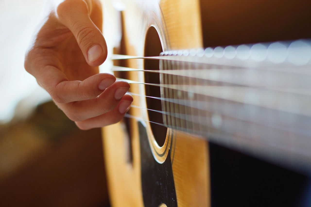 Image of a hand playing a guitar to convey Best Acoustic Guitar Brand