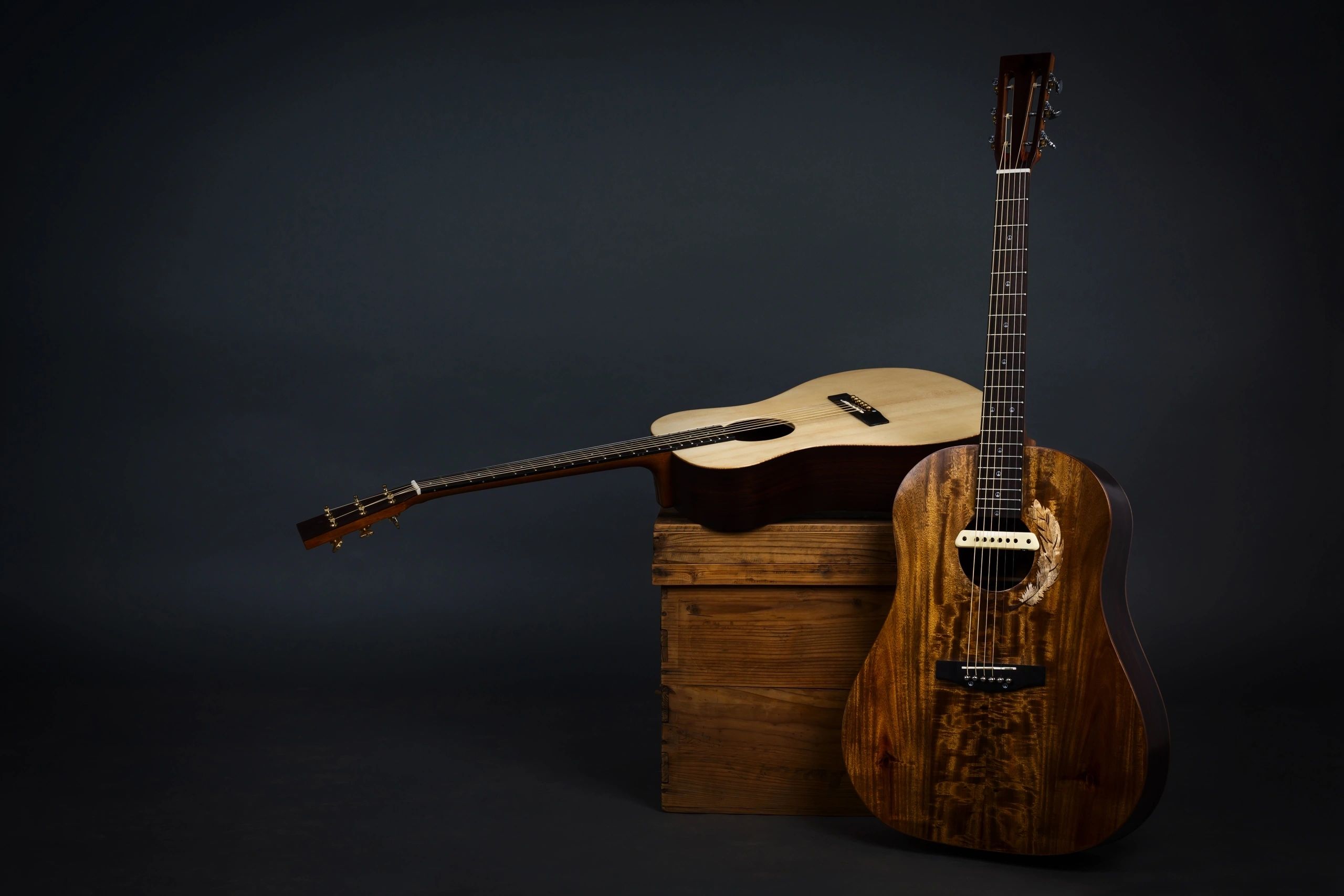 Acoustic guitar on a chair and close-up brown guitar in black background.